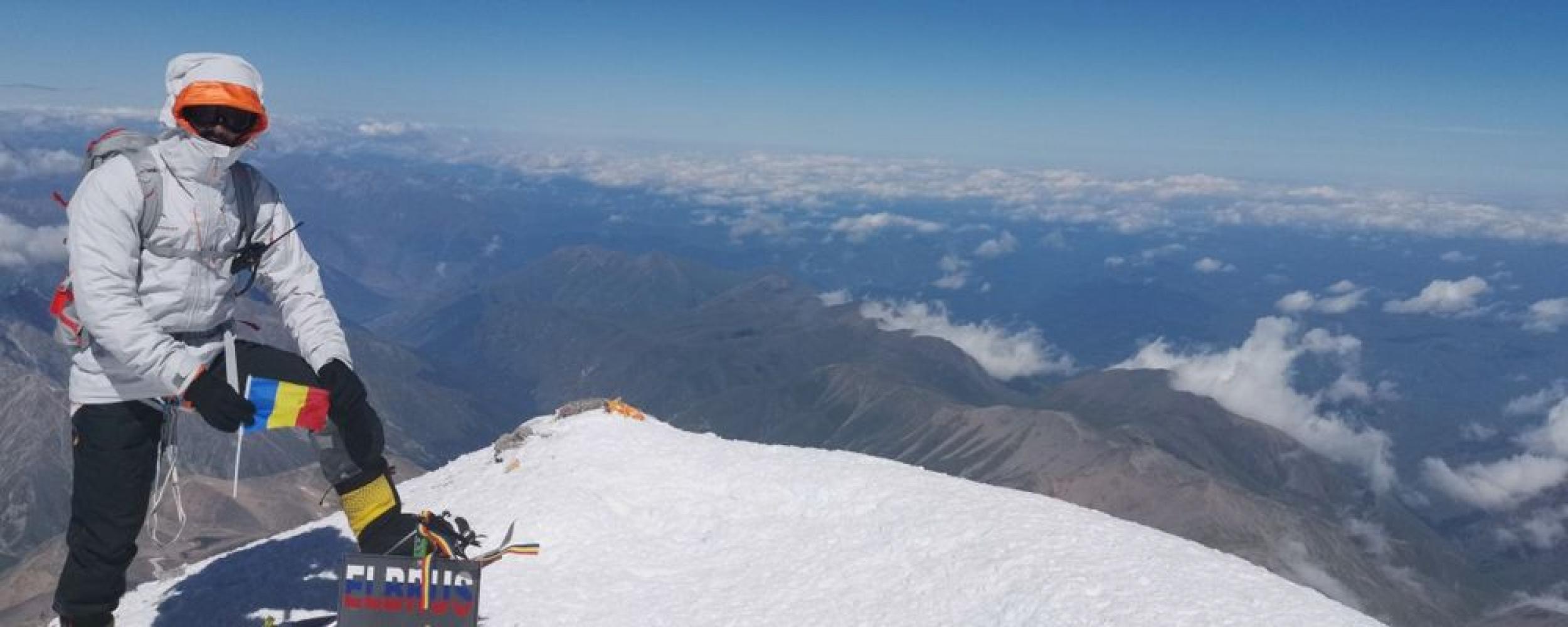 Alpinist pe creastă înzăpezită, cu drapelul României